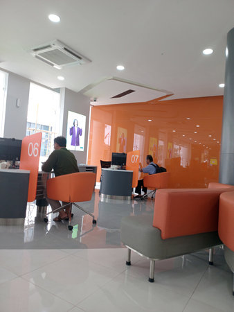 A modern office interior featuring orange partitions, sleek furniture, and people working at desks. The space is bright and inviting, with a contemporary design.の写真素材