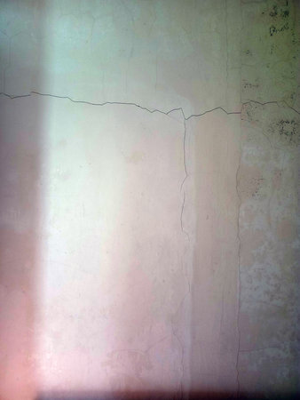 A cracked and weathered wall with visible texture and discoloration.の写真素材