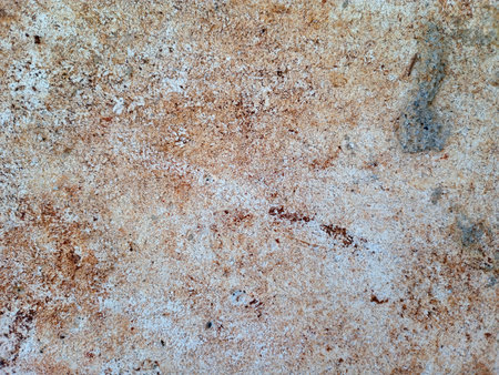 Close up of a textured, weathered concrete surface with rust stains.