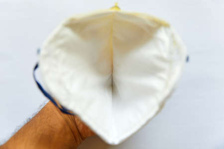Hand holding the inside of a Face Mask isolated on a white background with blue strapsの写真素材