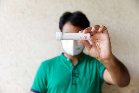 Man wearing a Green T-shirt holds a cell phone while looking surprisedの写真素材