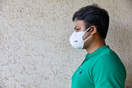 Man wearing a Green T-shirt holds a cell phone while looking surprisedの写真素材