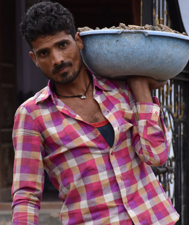 Karakbel, Madhya Pradesh/India : A man holding a tub full of concrete and cementのeditorial素材