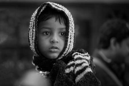 Black and white headshot portrait of a small boy with expressive eyes who is looking away from the cameraのeditorial素材