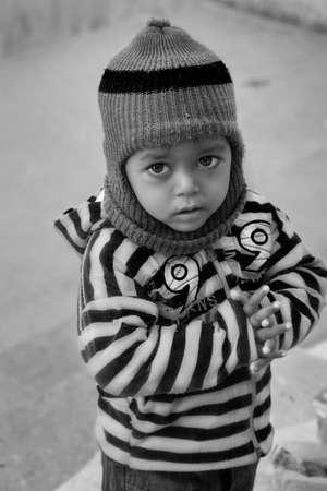Black and white portrait of a small cute boy doing Namaste by joining his both hands and looking towards the cameraのeditorial素材