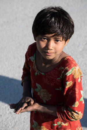 Portrait of small girl in red floral clothes, smiling towards the camera with her hands joined as Namaste during daylightのeditorial素材