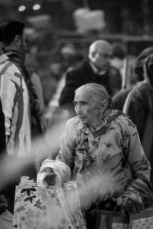 Black and white photograph of an old lady with wrinkled face walkingのeditorial素材
