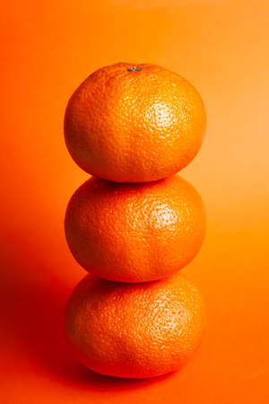 3 oranges placed one on top of the other in a closed plane and a background of the same orange color. Concept real foodの写真素材