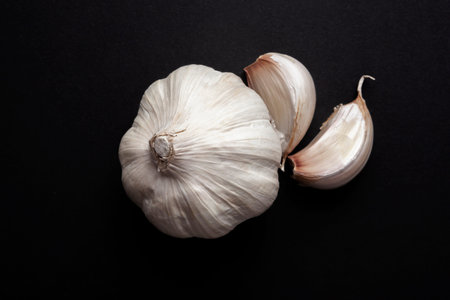still life of garlic heads and garlic cloves on black background. healthy ingredients food concept.
