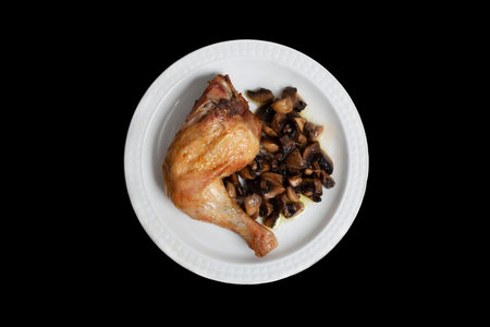 roasted chicken leg served with mushrooms on a plateの写真素材