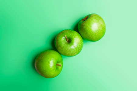 top view of 3 green apples on green backgroundの写真素材