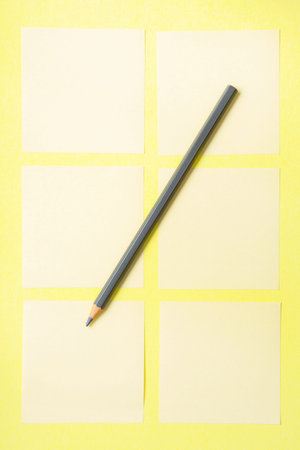 gray pencil on yellow background with blank notes to write reminders