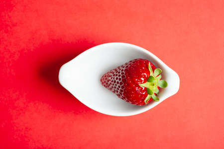 top view of a strawberry in bowl on red background. Copy space.の写真素材