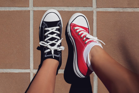 2-color sneakers, red and black. View from above pinning on girl