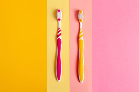 toothbrushes in two colors, yellow and pink. 2 color background. Copy space.