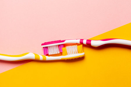 toothbrushes in two colors, yellow and pink. 2 color background. Copy space.