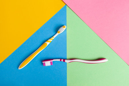 toothbrushes in two colors, yellow and pink. Multi-colored background. Copy space.の写真素材