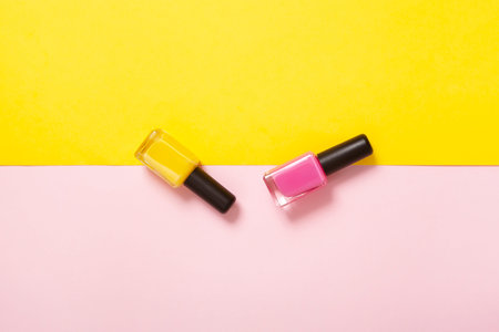 top view pink and yellow nail polish with background of the same color with copy space. Minimal...