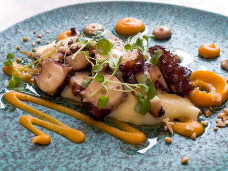 very elaborate dish of octopus cooked with sauce served in restaurantの写真素材