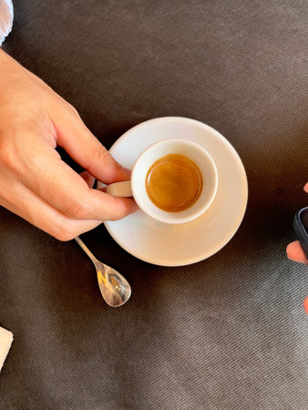 top view of a man drinking a single coffee from a small cup in a coffee shop
