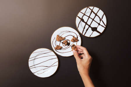 top view of hand picking up a piece of cookie with 3 chocolate platesの写真素材
