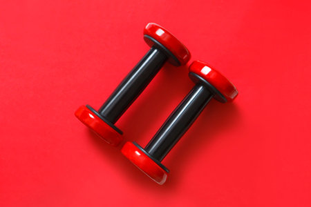 red exercise dumbbells isolated on red background