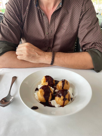 man eating profiteroles at a restaurant table