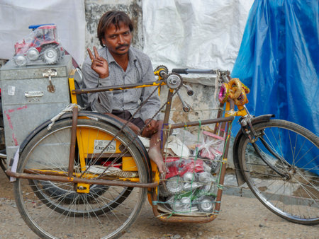 Pushkar, Rajasthan / India - November 5, 2019 : A Happy Indian handicap man selling toys on wheelchair showing victory signのeditorial素材