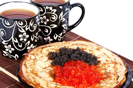 Cups with tea and a pile of pancakes with caviar on a plateの写真素材