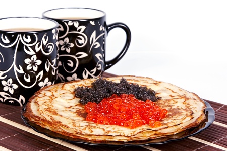 Cups with tea and a pile of pancakes with caviar on a plateの写真素材
