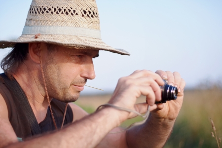 The man in a straw hat with the camera has a rest outdoorsの写真素材