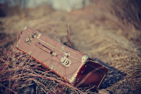 Old fashioned forgotten a suitcase, lie forgotten in a faded grass.の写真素材