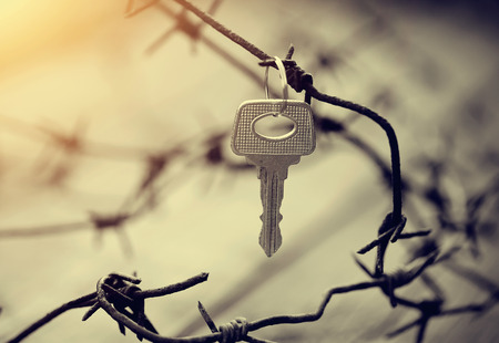 The key hangs on a rusty barbed wire.の写真素材