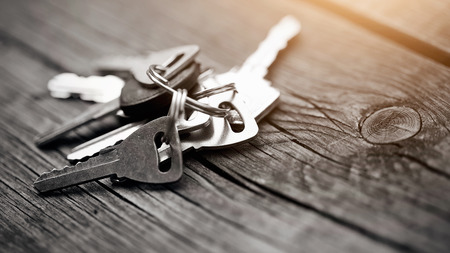 Bunch of keys lies on a wooden table.の写真素材