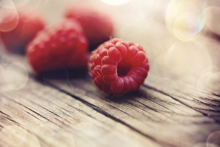 Red ripe berries of raspberry lie on a wooden table.の写真素材