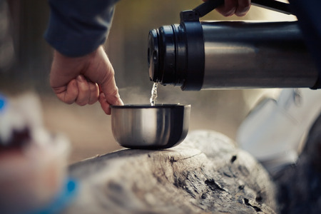 Pouring of tea from a cup on a picnic.の写真素材