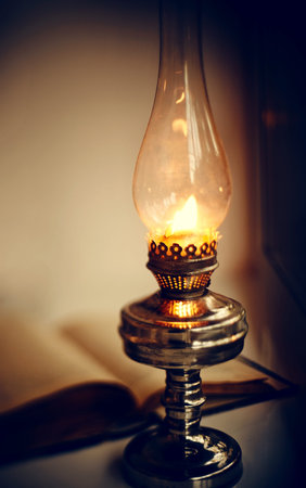 Vintage kerosene lamp burning and old open bookの写真素材
