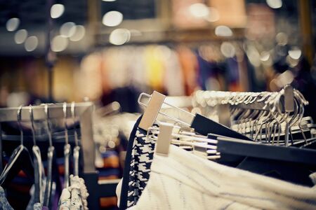 Shopping in store. Clothes on hangers in shop for sale. Blur background. Fashionable clothes in a boutique. Various clothing on market.の写真素材