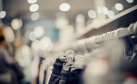 Shopping in store. Clothes on hangers in shop for sale. Blur background. Fashionable clothes in a boutique. Various clothing on market.の写真素材