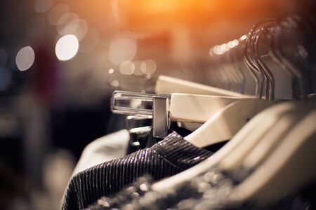 Shopping in store. Clothes on hangers in shop for sale. Blur background. Fashionable clothes in a boutique. Various clothing on market.の写真素材