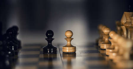 Two pieces on the chessboard are pawns: black and white. Wooden chess pieces on the chessboard. Intellectual game -chess. Chess pieces on the Board. A game of chess.の写真素材