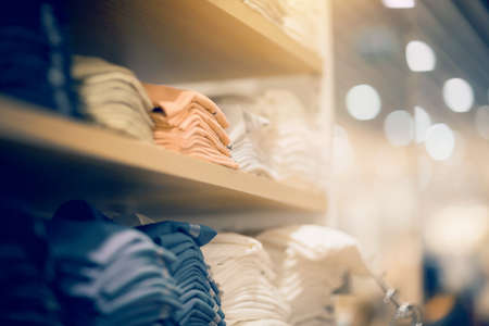 Stacks of clothes. Shopping in store. Clothing on the shelves in shop for sale. Blur background. Fashionable clothes in a boutique. Various clothing on market.の写真素材