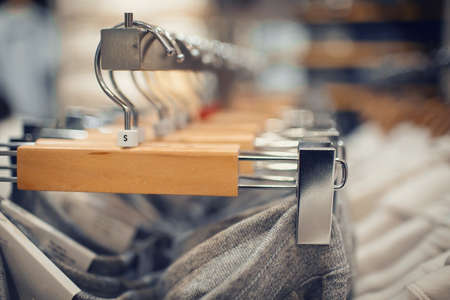 Shopping in store. Clothes on hangers in shop for sale. Blur background. Fashionable clothes in a boutique. Various clothing on market.の写真素材