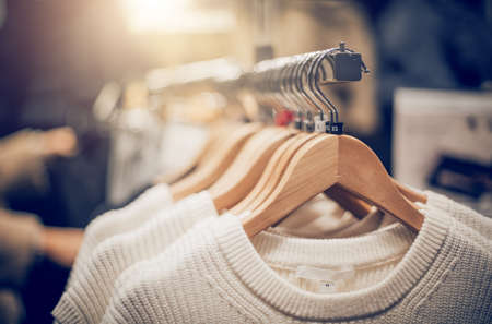 Sweaters on hangers. Shopping in store. Clothes on hangers in shop for sale. Blur background. Fashionable clothes in a boutique. Various clothing on market.の写真素材