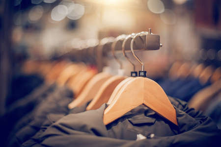 Hangers with clothes on the rail in the store. Shopping in store. Clothes on hangers in shop for sale. Blur background. Fashionable clothes in a boutique. Various clothing on market.の写真素材