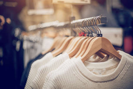 Sweaters on hangers. Shopping in store. Clothes on hangers in shop for sale. Blur background. Fashionable clothes in a boutique. Various clothing on market.の写真素材