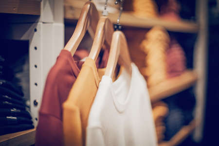 T-shirts on hangers. Stacks of clothes. Shopping in store. Clothes on hangers in shop for sale. Blur background. Fashionable clothes in a boutique. Various clothing on market.の写真素材