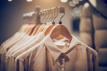Shirts on hangers. Shopping in store. Clothes on hangers in shop for sale. Blur background. Fashionable clothes in a boutique. Various clothing on market.の写真素材