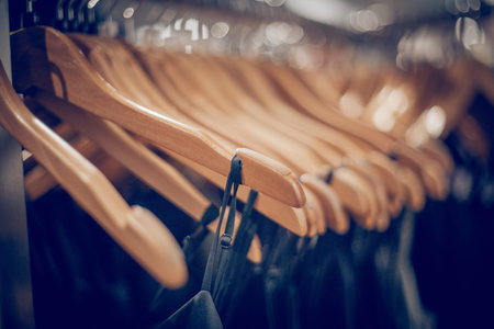 Wooden hangers with clothes on the rail in the store. Shopping in store. Clothes on hangers in shop...