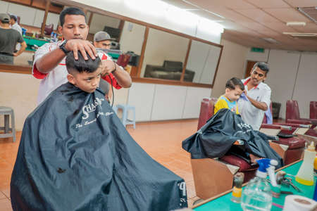 Muadzam Shah, Malaysia - August 14th, 2017 : Little boy getting warber while sitting haircut on chair at barbershop.のeditorial素材